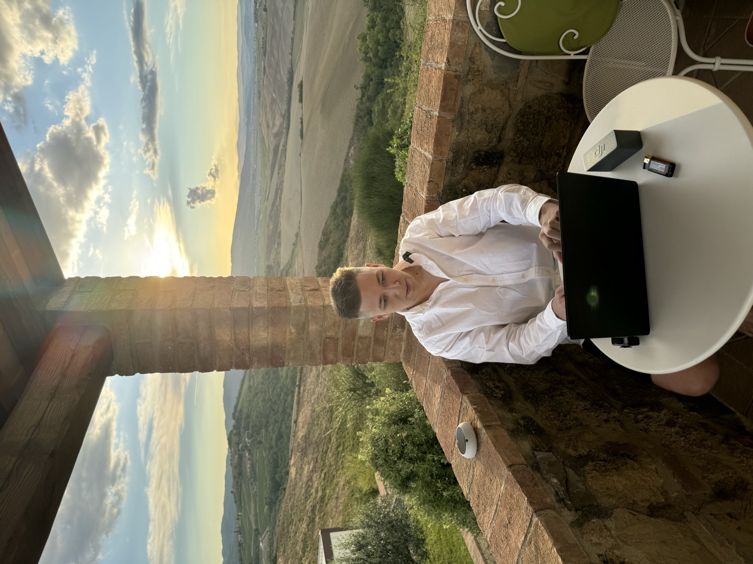 Artem working on a laptop at sunset over the Tuscan hills